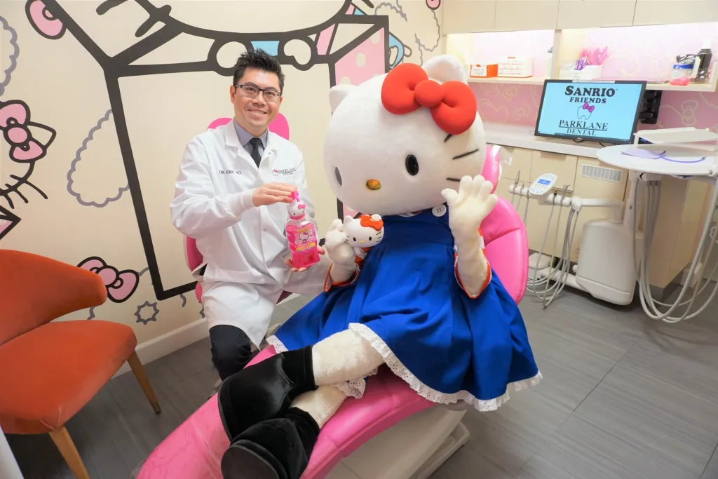 Hello Kitty and cosmetic dentist Dr. Eric To teaching rinsing with mouthwash in Hello Kitty themed dental room