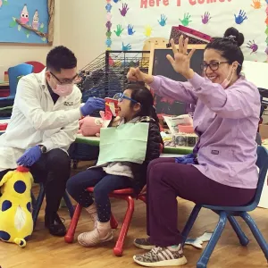 Cosmetic doctor conducting dental exam on pediatric student at local school