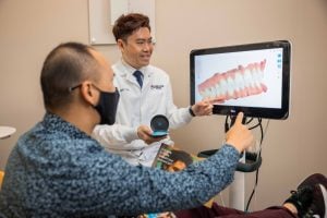 Parklane Dental - Dr. Eric To mostrando Invisalign a un paciente adulto