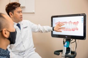 Cosmetic Dentist Dr. Eric To explaining gum disease with swollen gum simulation for dental exam at Parklane Dental