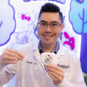 Cosmetic dentist holding Invisalign clear aligners and exclusive Hello Kitty dental case