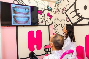Cosmetic dentist with male adult patient for Smile Makeover consultation on dental implants and braces and crowns in Hello Kitty themed room