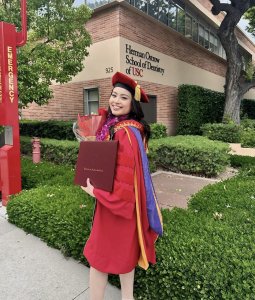 Dr. Lewen Ma in her USC Graduation Gown posing in front of the USC School of Dentistry